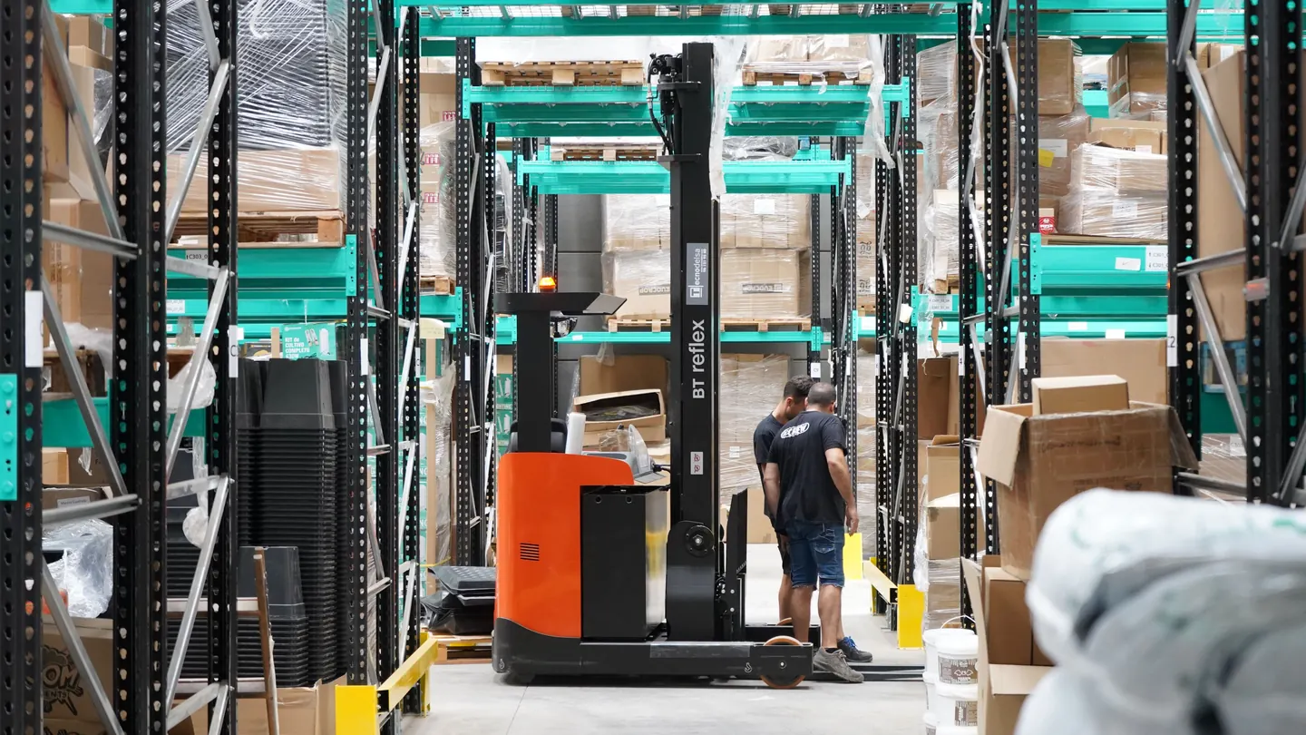 Workers and a forklift along a warehouse aisle