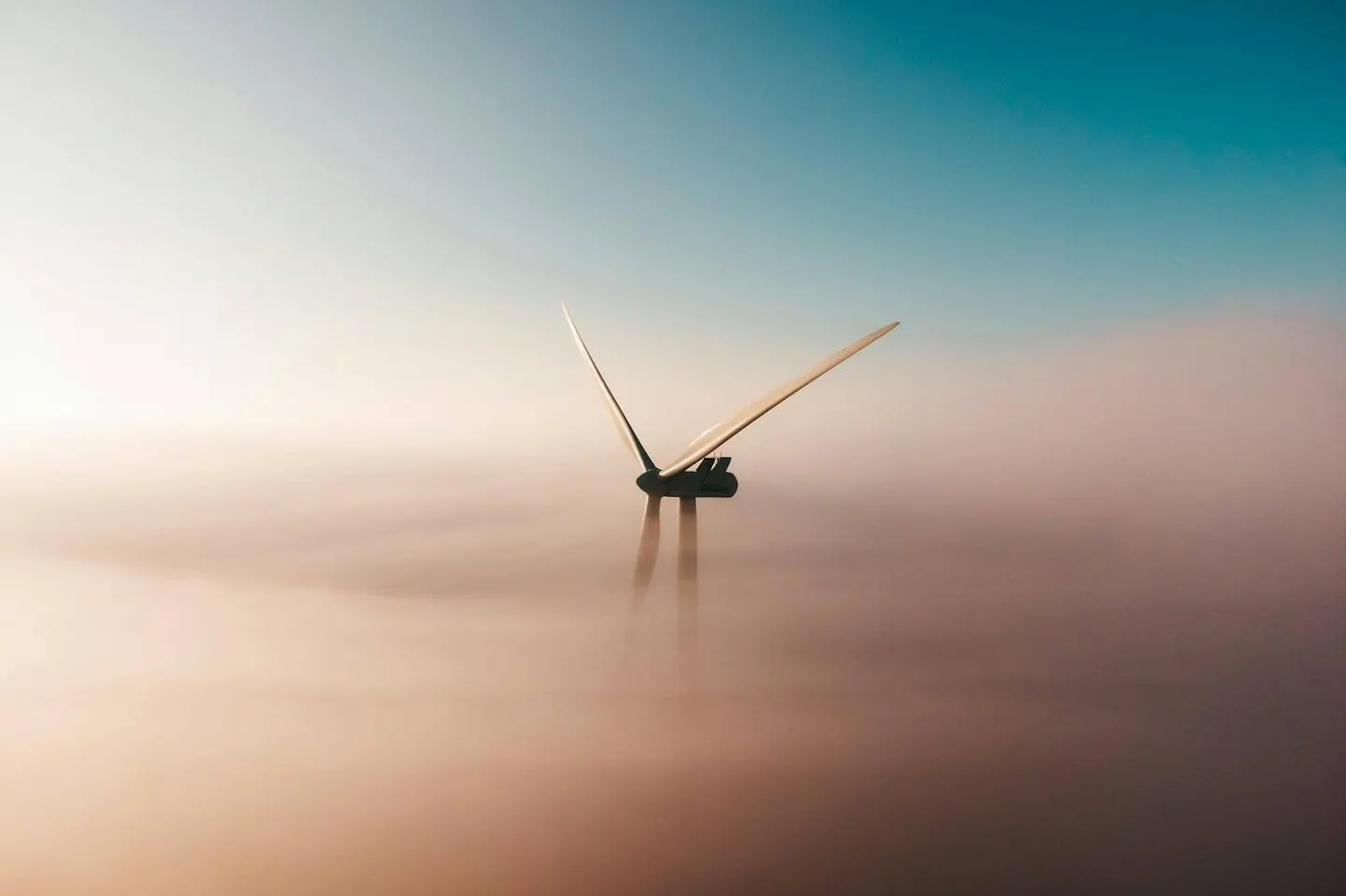 A wind turbine standing in heavy fog